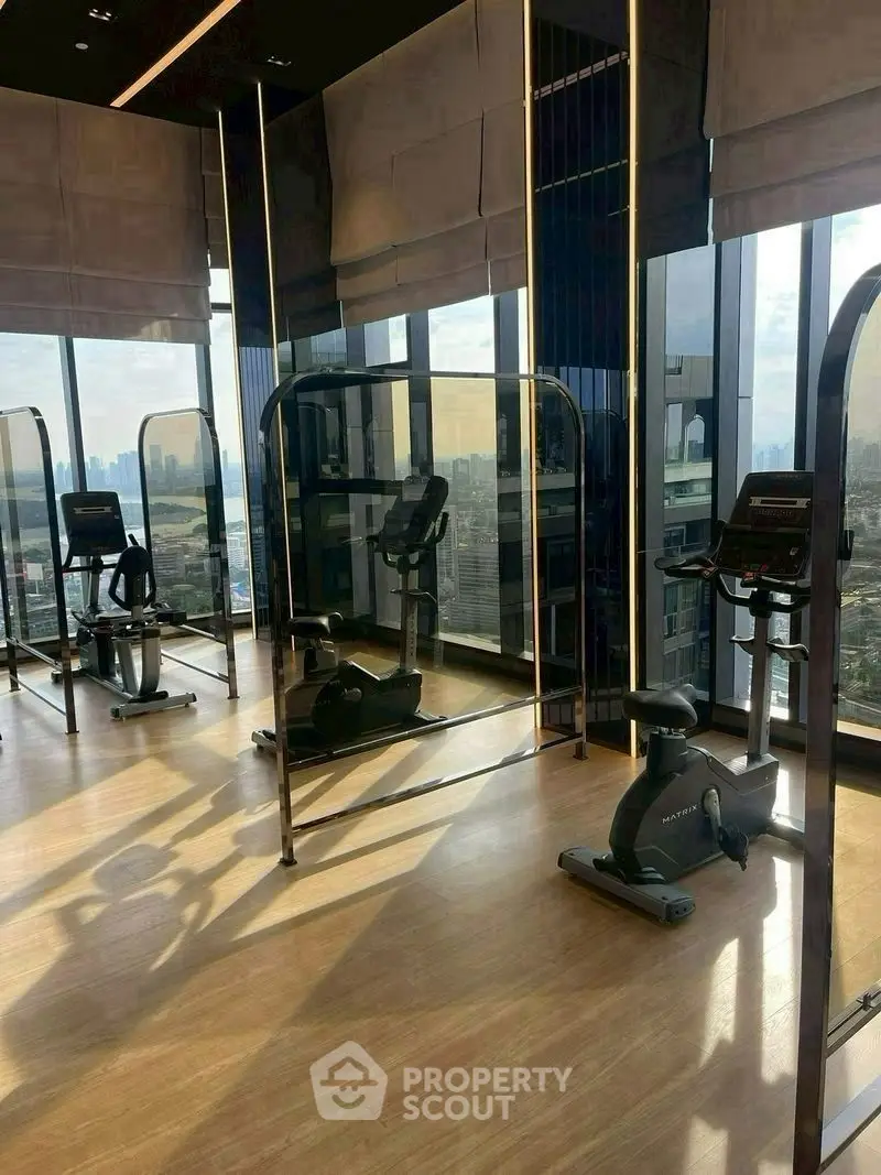 Modern gym with city view and exercise bikes in luxury high-rise building.