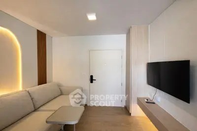 Modern living room with sleek design, featuring a cozy sofa, wall-mounted TV, and stylish lighting.