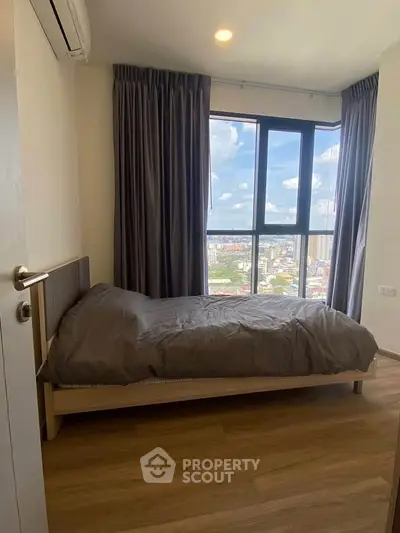Cozy bedroom with city view, featuring a comfortable bed and large window.