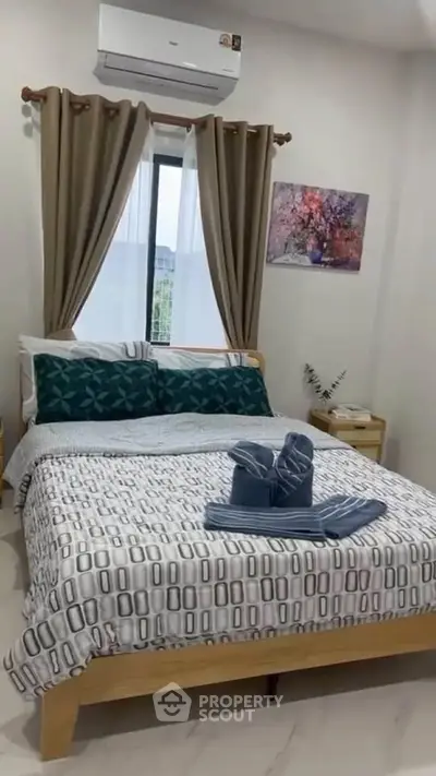 Cozy bedroom with stylish decor and air conditioning, featuring a comfortable bed and elegant curtains.