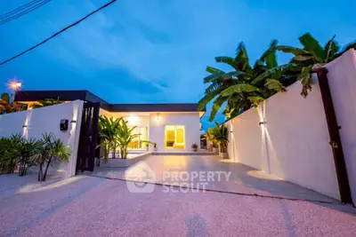 Modern villa with lush garden and spacious driveway at dusk