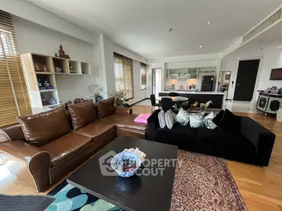 Spacious living room with modern decor and open kitchen layout, featuring elegant furniture and natural light.