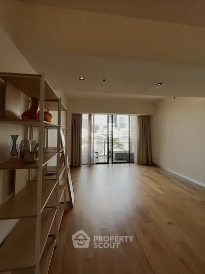 Spacious living room with wooden flooring and large windows offering city views.