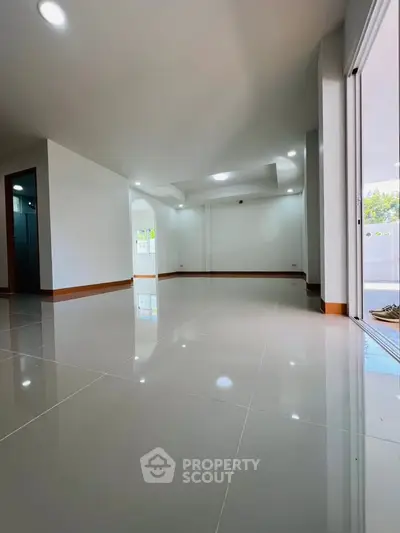 Spacious modern living room with glossy tiled floors and bright natural lighting.