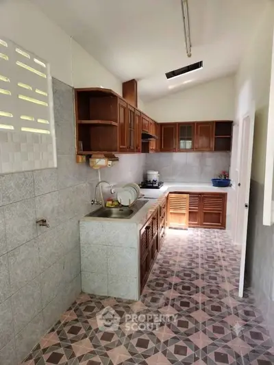 Charming kitchen with wooden cabinets and patterned tile flooring in a cozy home.