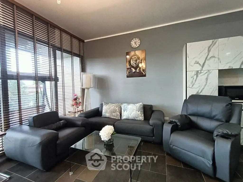 Modern living room with sleek black furniture and large windows for natural light.