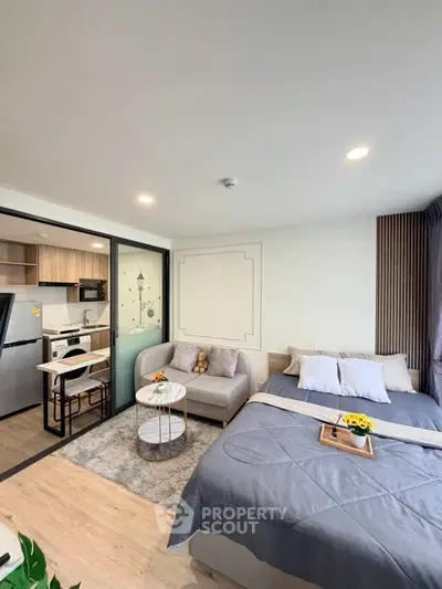 Modern studio apartment with open layout, featuring cozy bed, stylish sofa, and compact kitchen area.
