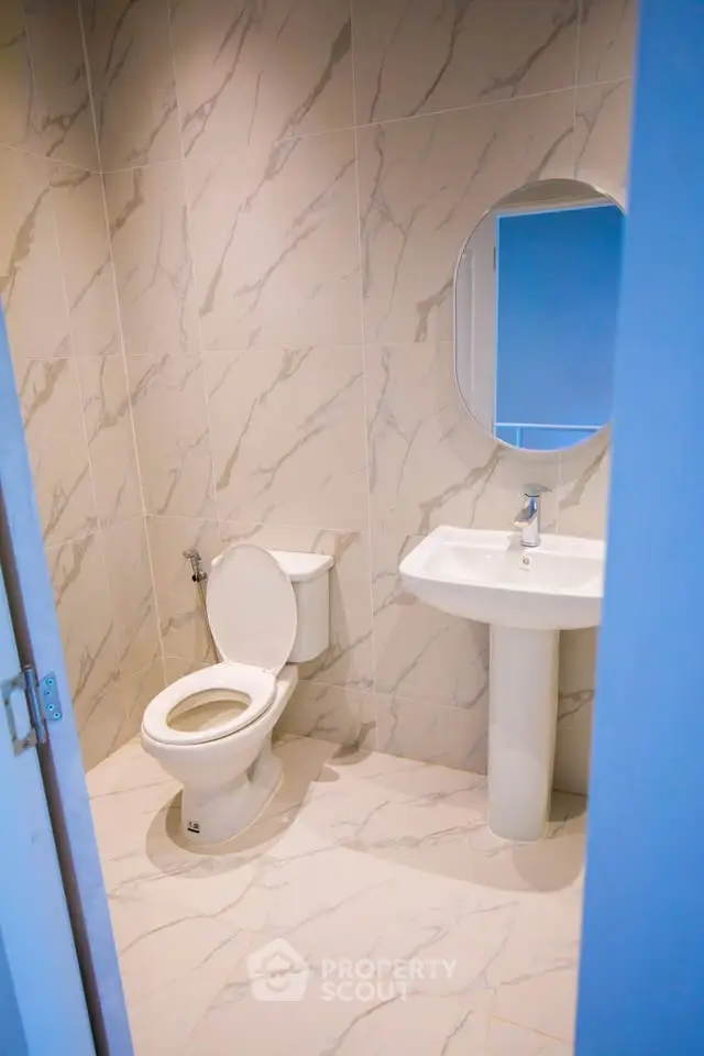Modern bathroom with marble tiles and round mirror