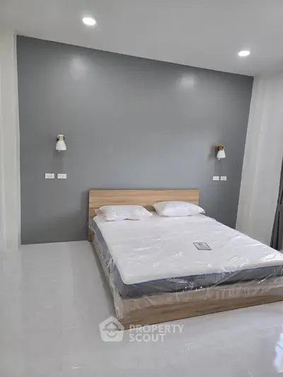 Modern bedroom with minimalist design featuring a comfortable bed and stylish wall lighting.
