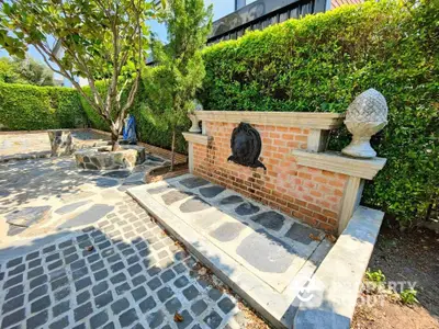 Charming garden area with brick fountain and lush greenery, perfect for outdoor relaxation.