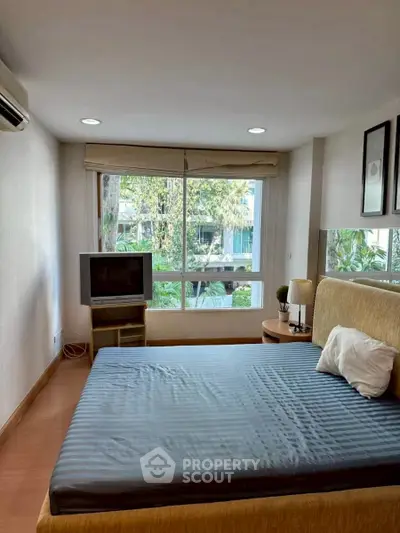 Cozy bedroom with large window and garden view, featuring a comfortable bed and modern decor.