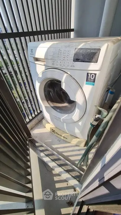 Compact washing machine on a balcony with modern railing, perfect for urban living spaces.
