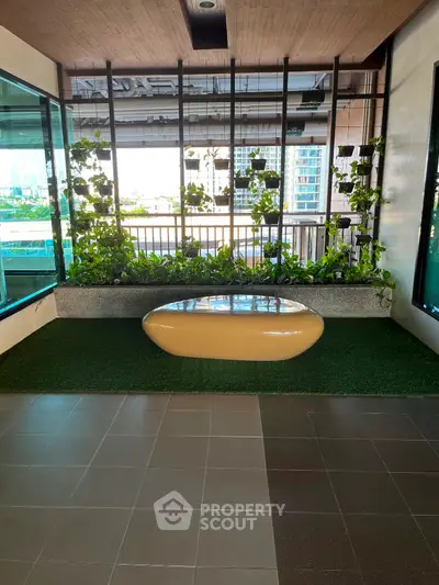 Modern balcony with green plants and stylish seating, offering a serene urban view.