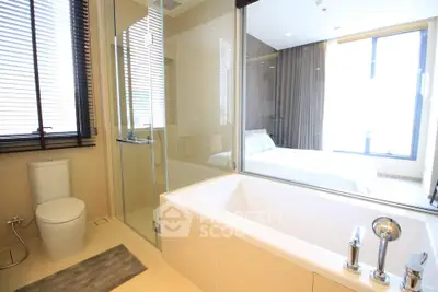 Luxurious bathroom with modern bathtub and glass shower, adjacent to a bright bedroom with large windows.