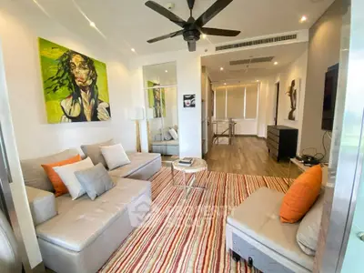 Modern living room with stylish decor and vibrant artwork, featuring a cozy sectional sofa and ceiling fan.