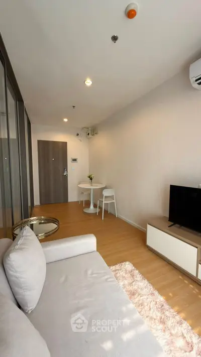 Modern living room with cozy sofa, TV, and dining area in stylish apartment.