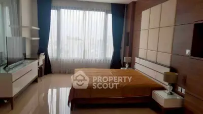 Luxurious bedroom with large window and modern furnishings in high-rise apartment.
