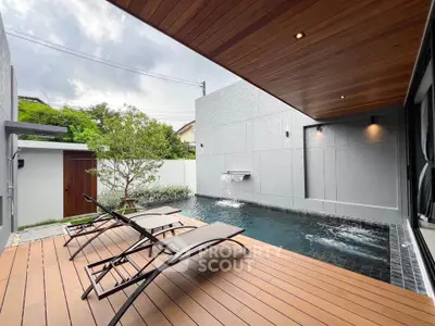 Luxurious modern poolside deck with sleek loungers and serene water feature