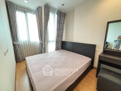 Cozy bedroom with modern furnishings and ample natural light from large windows.