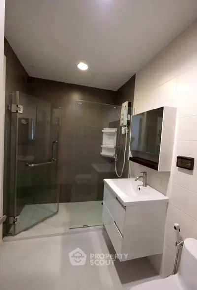 Modern bathroom with glass shower and sleek vanity in contemporary apartment.