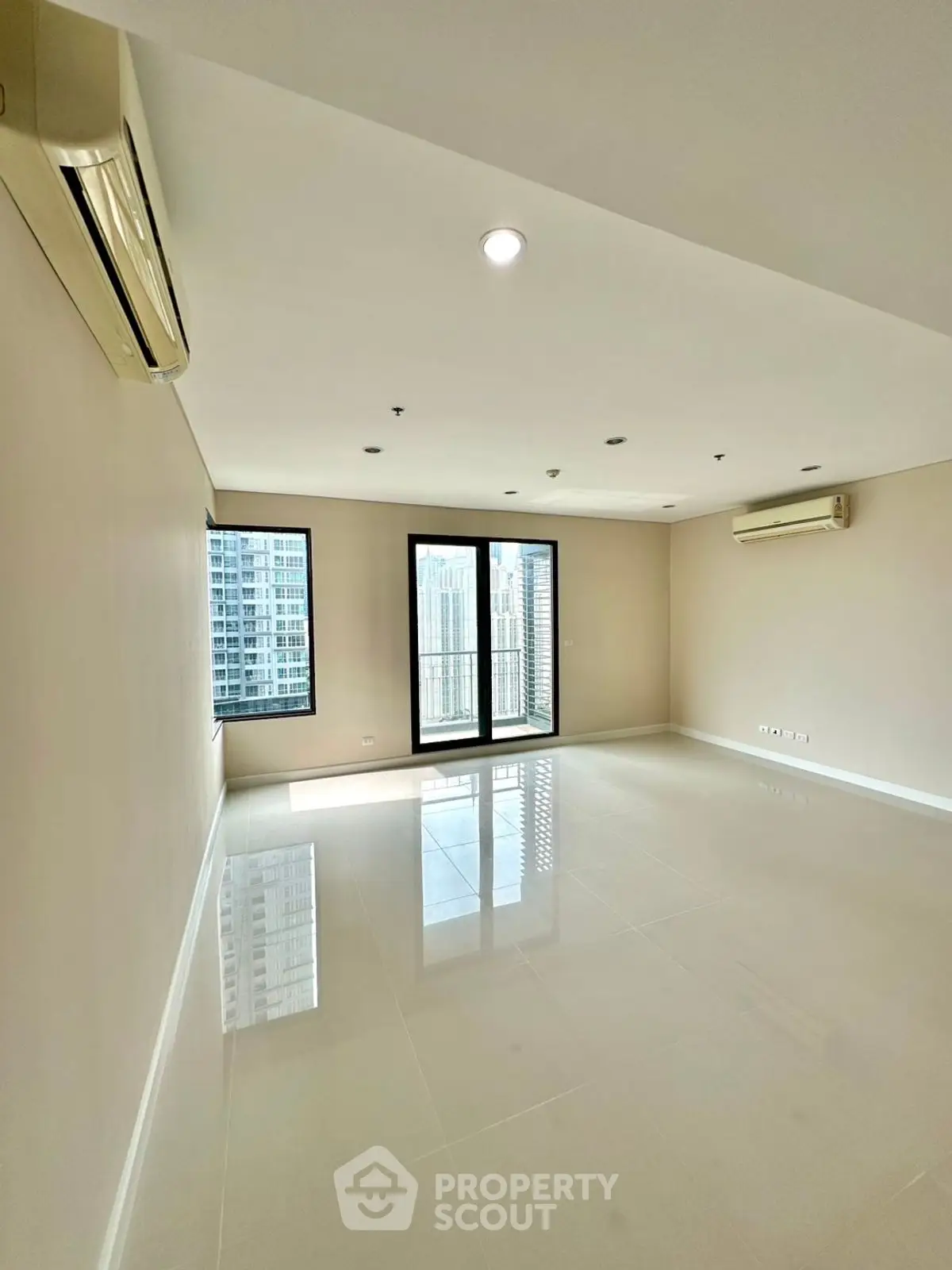 Spacious modern living room with large windows and city view in high-rise apartment.