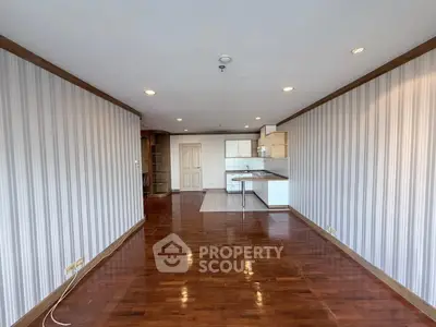 Spacious open-plan living room with wooden flooring and modern kitchen area.