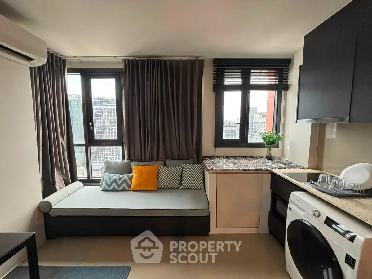 Modern apartment interior with cozy seating and city view, featuring a washing machine and stylish decor.
