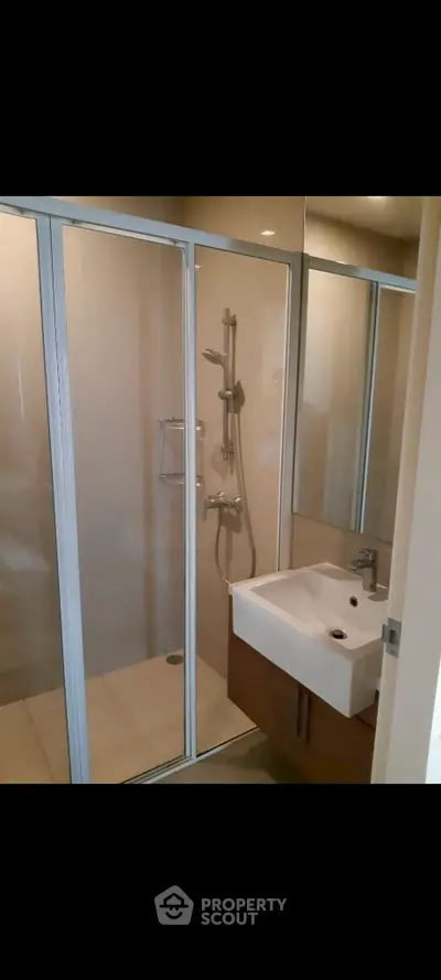 Modern bathroom with glass shower enclosure and sleek sink design.