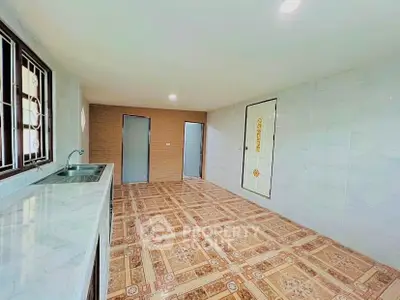 Spacious kitchen with tiled flooring and ample natural light, featuring a sleek countertop and modern fixtures.