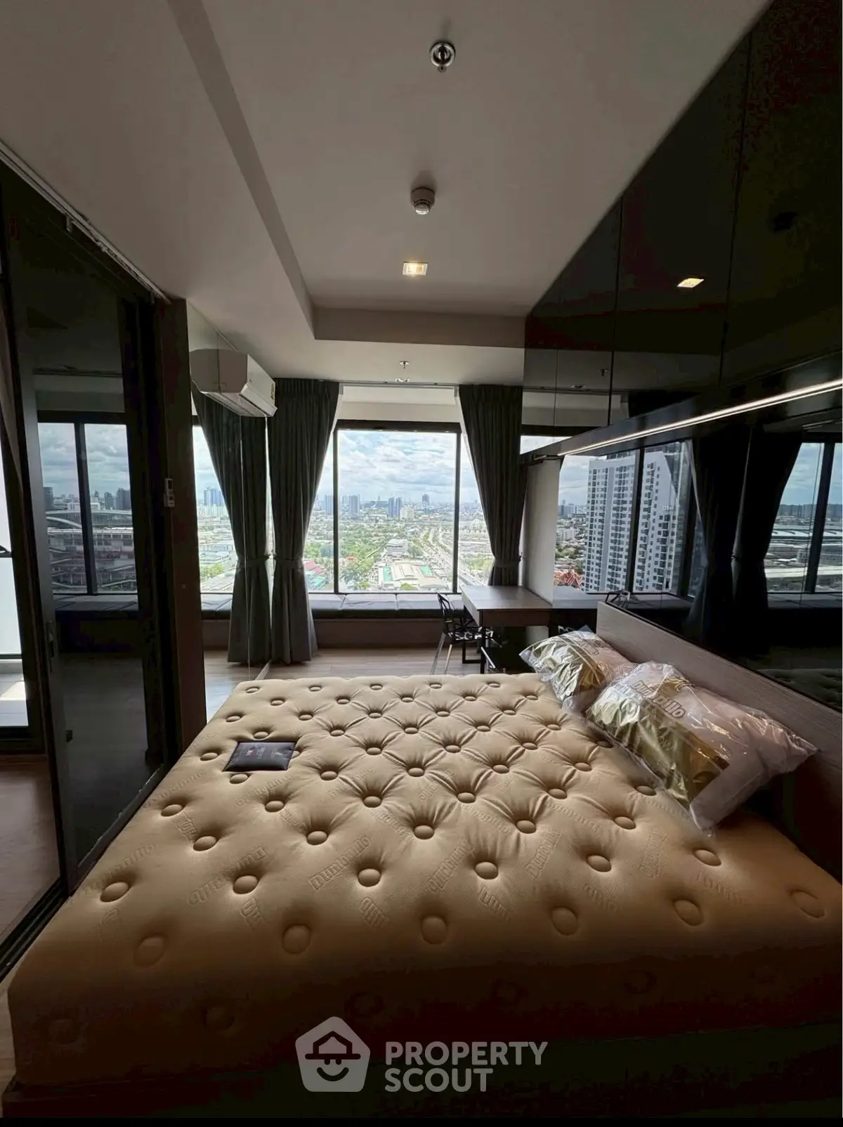 Luxurious bedroom with stunning city view and modern decor in high-rise apartment.
