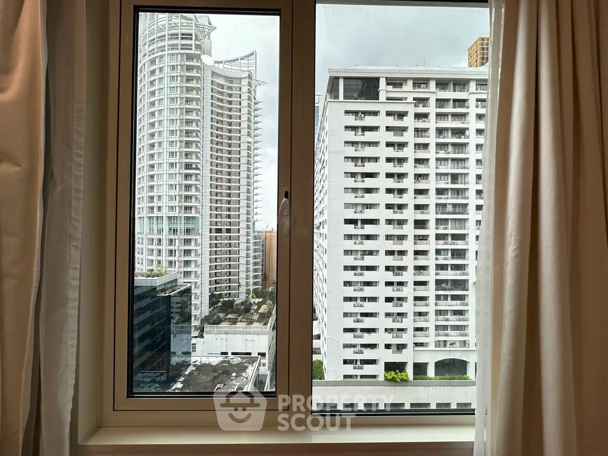 Stunning cityscape view from a modern apartment window, showcasing high-rise buildings and urban architecture.