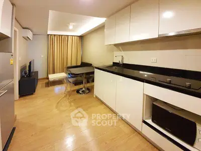 Modern kitchen with sleek cabinets and dining area in open layout apartment.