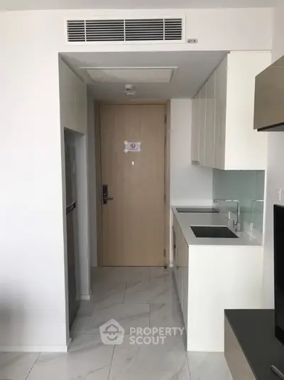 Modern compact kitchen with sleek white cabinets and integrated appliances