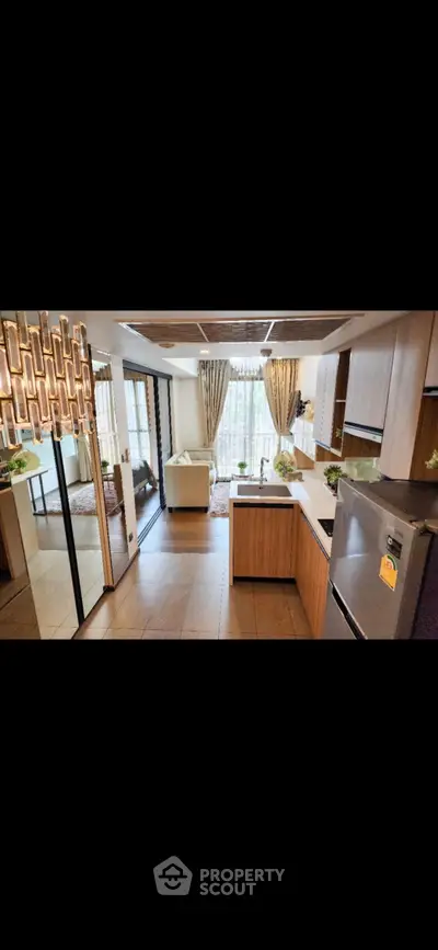 Modern open-layout kitchen with stylish lighting and cozy living area, perfect for entertaining.