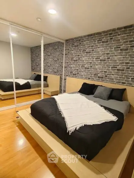 Modern bedroom with mirrored closet and stylish brick accent wall