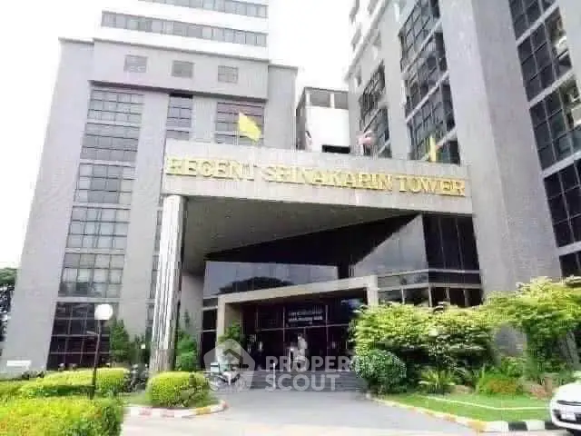 Modern commercial building entrance with sleek design and lush landscaping.