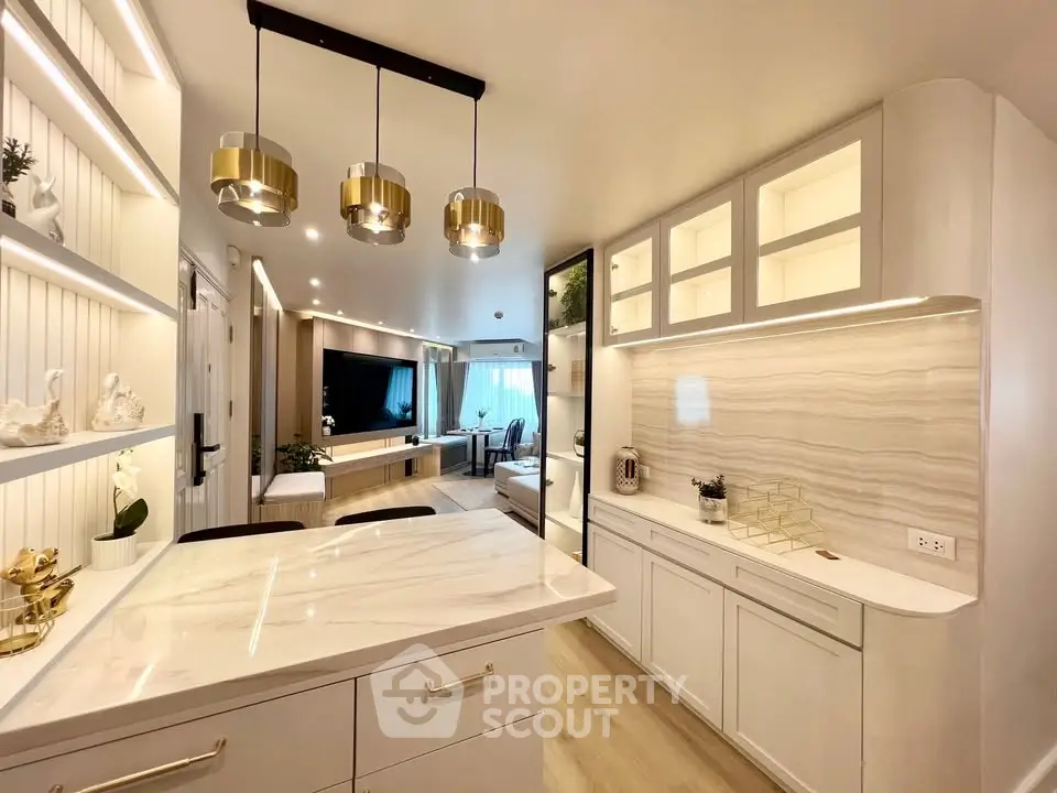 Luxurious modern kitchen with marble countertops and elegant lighting in open-plan living space.