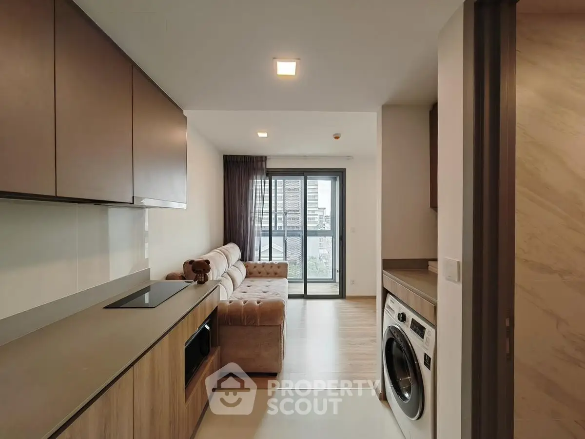 Modern apartment with open kitchen and cozy living area featuring a washing machine and city view balcony.