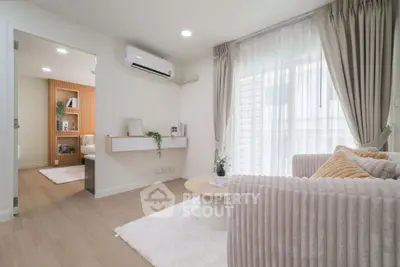 Modern living room with cozy sofa, air conditioning, and natural light from large windows.