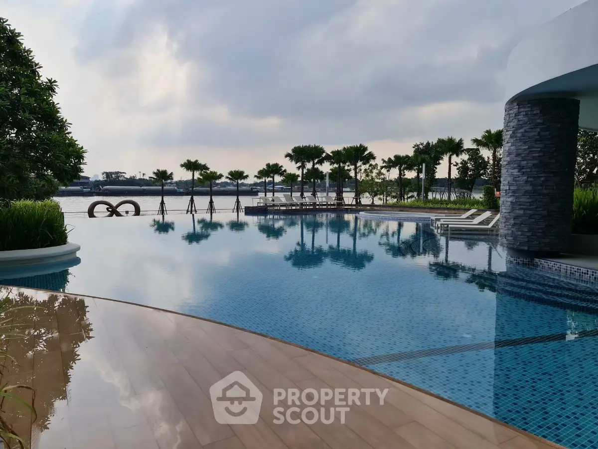 Luxurious infinity pool with stunning waterfront view and lush palm trees.