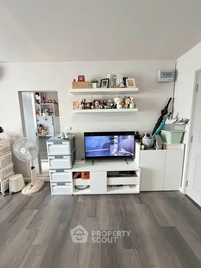 Modern living room with sleek storage, TV setup, and stylish decor on floating shelves.