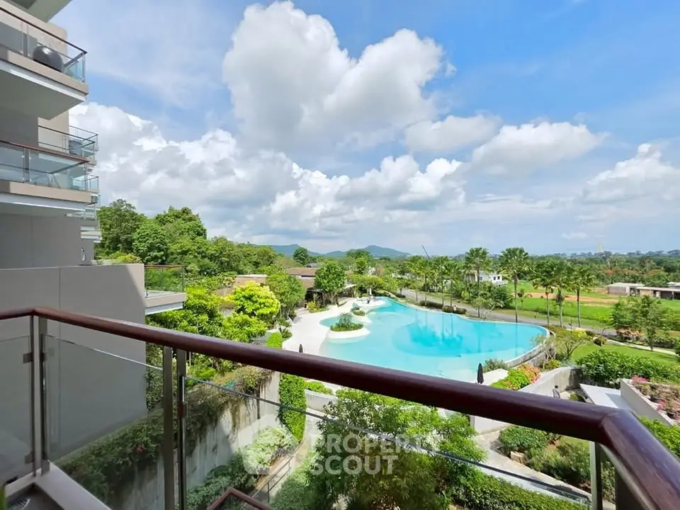 Luxurious balcony view overlooking a stunning pool and lush greenery, perfect for relaxation.