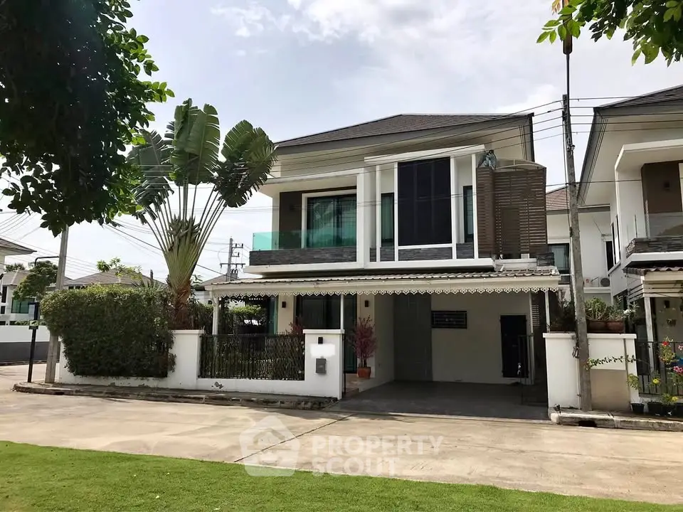 Modern two-story house with lush garden and spacious driveway in a serene neighborhood.