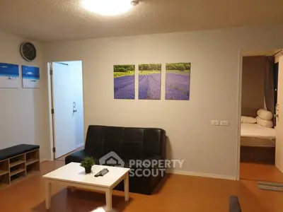 Cozy living room with modern decor and wall art, leading to a comfortable bedroom.