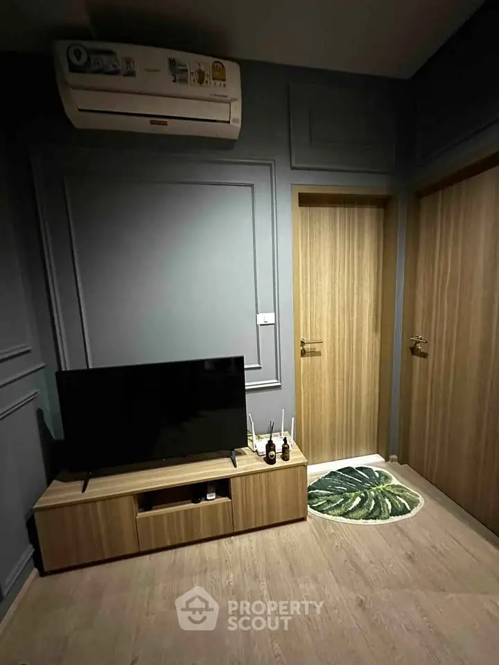 Modern living room with sleek TV stand and air conditioning, featuring stylish wooden doors and elegant wall paneling.