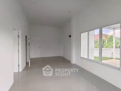 Spacious empty room with large window and garden view, perfect for customization.