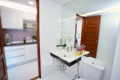 Modern bathroom with sleek fixtures and adjacent kitchen view