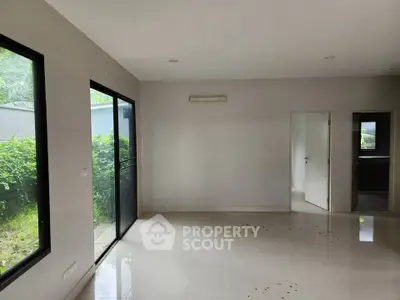 Spacious empty room with large windows and garden view, perfect for customization.