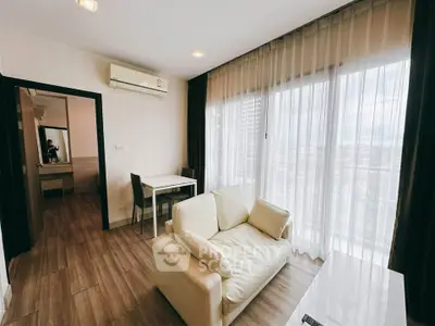 Modern living room with large windows and cozy seating in a stylish apartment.