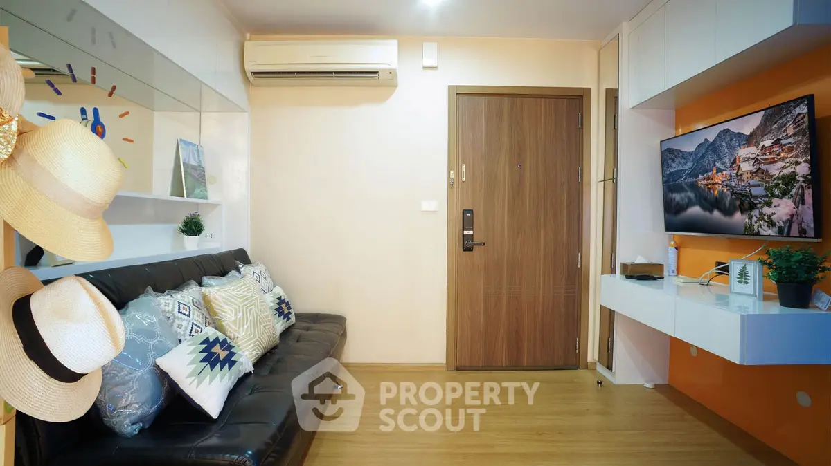 Modern living room with stylish decor and wall-mounted TV, featuring cozy seating and air conditioning.
